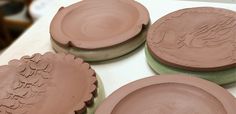 four clay plates sitting on top of a table covered in frosting and icing