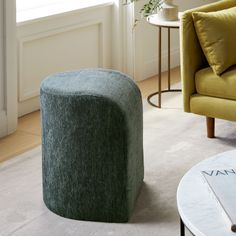 a living room with a green chair and ottoman