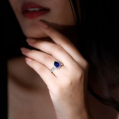 a close up of a person wearing a ring with a heart shaped stone on it