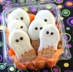 there are some ice cream cones with ghost faces on them in a plastic container for halloween treats