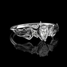 a white gold ring with three pear shaped diamonds in the center and leaves on each side