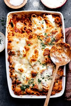 a casserole dish with meat, cheese and parmesan on the side