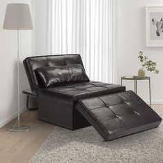 a black leather chaise lounge chair and footstool in a white living room