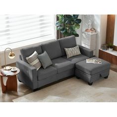 a living room scene with focus on the sectional sofa and footstool in the foreground