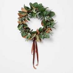 a wreath with green leaves and brown ribbon