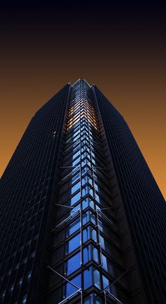 a very tall building with many windows on it's sides at night time in the city