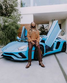 a man sitting on top of a blue sports car