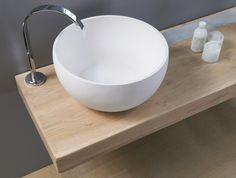 a white bowl sink sitting on top of a wooden counter next to a faucet