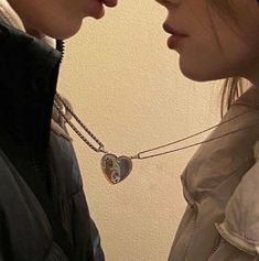 two people standing next to each other and one has a heart shaped necklace on his neck