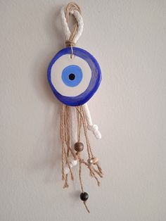 a blue and white evil eye hanging on the wall with beads around it's eyes