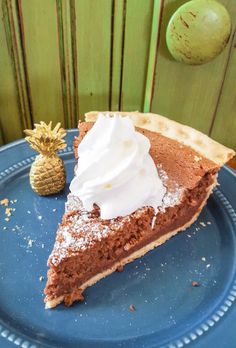 a slice of chocolate pie on a blue plate with a pineapple in the background