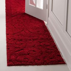 a red rug is on the floor in front of a white door