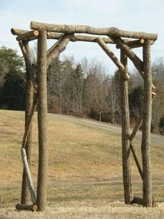 a giraffe standing next to a wooden structure on top of a grass covered field