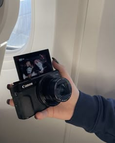 a person holding up a camera in front of an airplane window