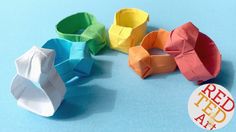 an origami ring is sitting on a blue surface next to several different colored paper rings