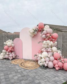 a pink and white wedding arch with balloons