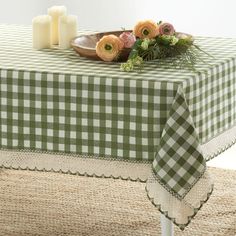 a green and white checkered table cloth with flowers on it, next to candles