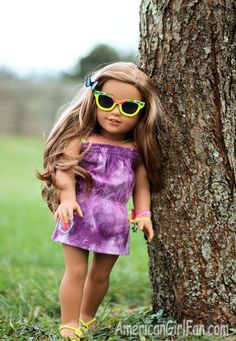 a doll wearing sunglasses leaning against a tree