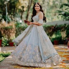 a woman in a white and gold gown is posing for the camera with her hand on her hip