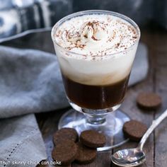 there is a drink with whipped cream and chocolate cookies on the table next to it