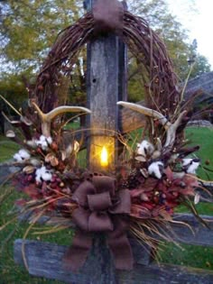 a wreath on top of a wooden post with a light in the middle and flowers around it