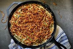 a large skillet filled with food on top of a blue and white towel next to a fork