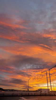 the sun is setting over an empty parking lot with street lights in the foreground