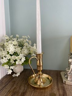 a white candle sitting on top of a wooden table next to a vase with flowers