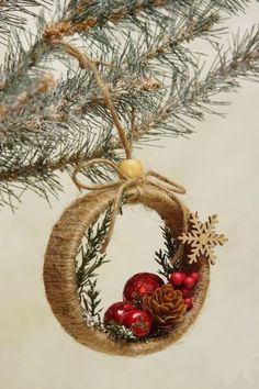 a christmas ornament hanging from a tree branch with pine cones and ornaments on it