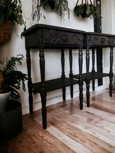 a black console table sitting on top of a hard wood floor next to potted plants