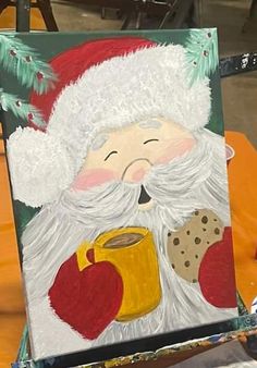 an easel with a painting of a santa holding a cup of coffee on it