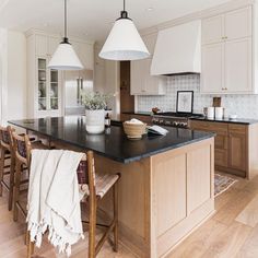 a large kitchen with an island in the middle and two pendant lights hanging over it