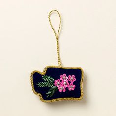 a blue ornament with pink flowers and green leaves hanging from a gold chain