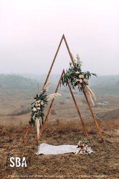 a wedding arch decorated with flowers and greenery in the middle of an open field