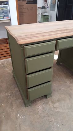 a green desk with three drawers on it