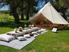 a tent set up in the middle of a field with pillows and blankets on it