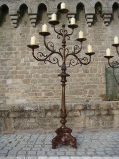 an ornate candle holder stands in front of a brick wall