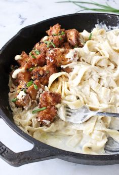 a skillet filled with pasta and meatballs on top of a marble countertop