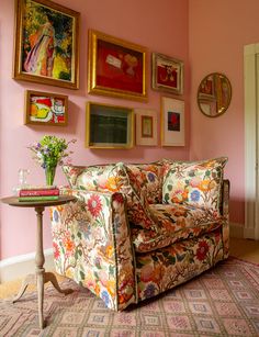 a living room with pink walls and pictures on the wall above the couch is decorated with flowers