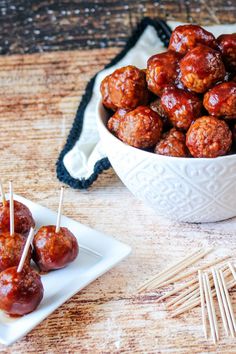 a white bowl filled with meatballs and toothpicks on top of a wooden table