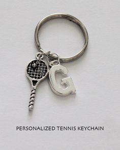 a tennis racquet and letter g keychain on a white background with the words personalized tennis keys chain