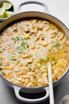 a large pot filled with soup next to limes and lemon wedges on the side