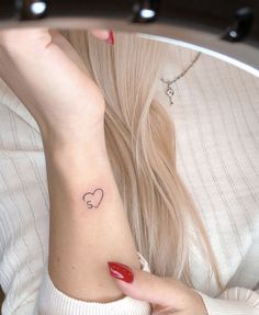 a woman with a heart tattoo on her wrist