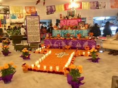 a room filled with lots of flowers and candles in front of a cross on the floor