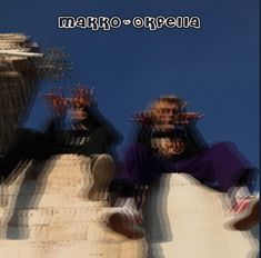 two young men sitting on top of a cement structure with their hands in the air