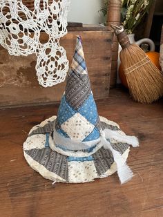 a small blue and white hat sitting on top of a wooden table next to a broom