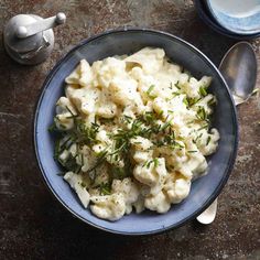 a bowl filled with macaroni and cheese on top of a table next to a spoon