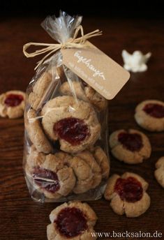 cookies in a bag with jam on the top and small ones around it sitting on a table