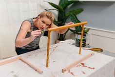 a woman is working on an unfinished piece of art with paint and wood planks