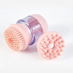 two pink hairbrushes sitting next to each other on a white surface, one has a plastic comb in it's middle